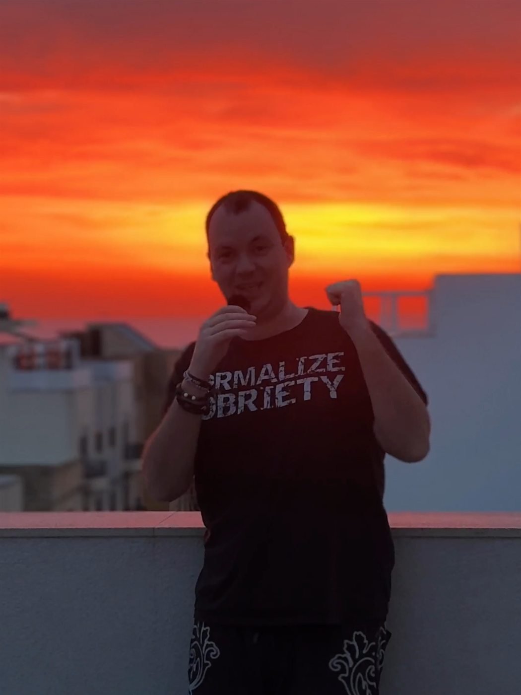 Markus steht nüchtern bei einem orangefarbenen Sonnenaufgang